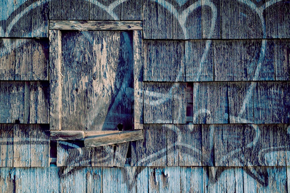 Weathered wooden wall with graffiti, highlighting architectural decay and urban art.