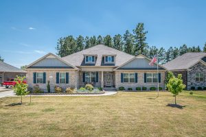 Charming brick family home in suburbia with American flag and manicured lawn.