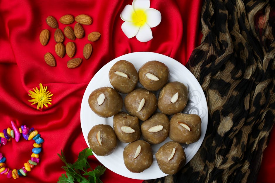 A plate of traditional Indian pinni sweets garnished with almonds, set against a vibrant red cloth.
