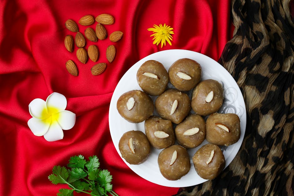 Indian sweets with almonds on red fabric, featuring floral decorations and nuts.