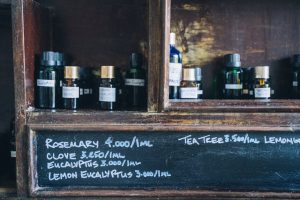 Close-up of essential oil bottles with handwritten labels on a wooden shelf, promoting natural aromatherapy and holistic health.